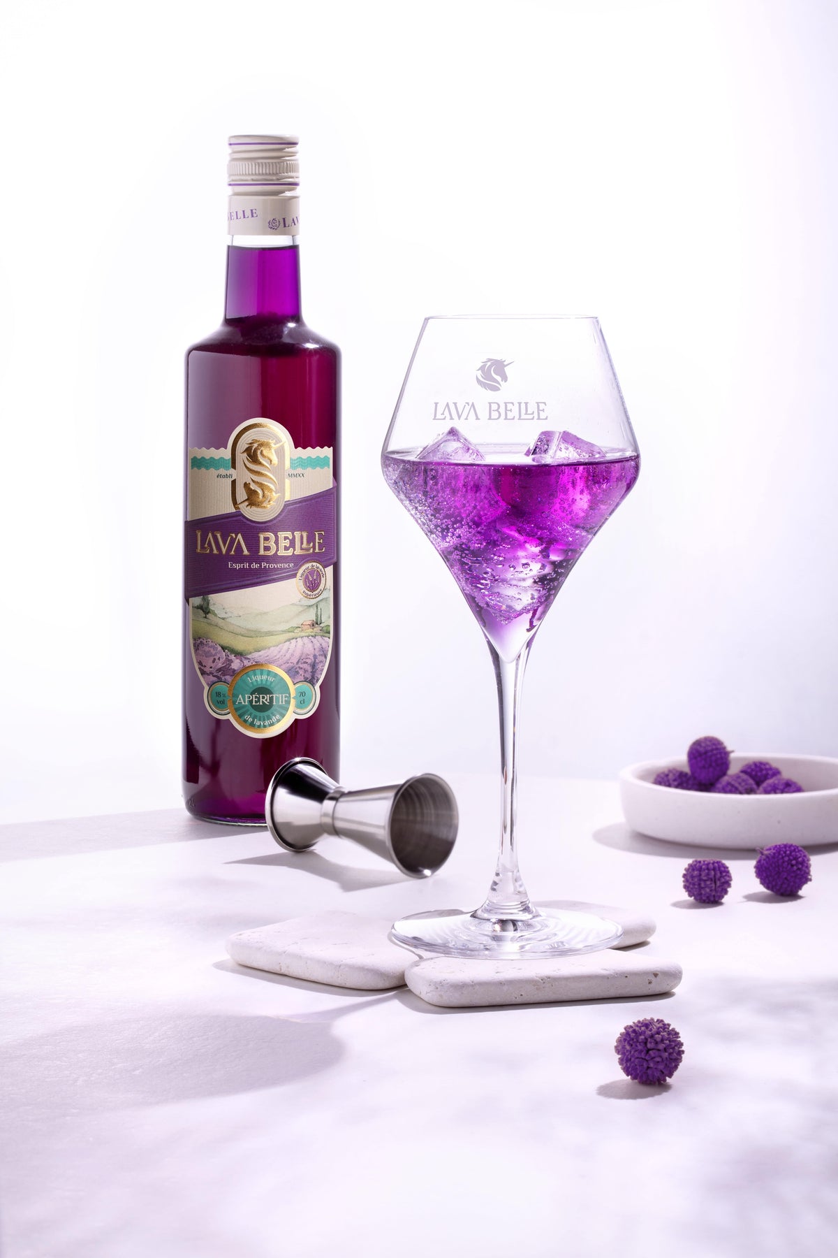Bouteille Lav'a Belle Apéritif et verre gravé rempli de spritz violet sur glace, avec doseur et déco violette